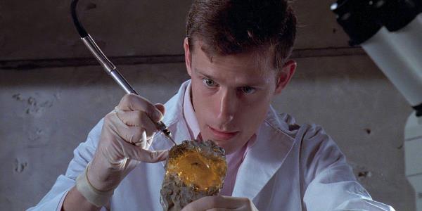 A scientist uses a tool on a mosquito encased in amber in Jurassic Park