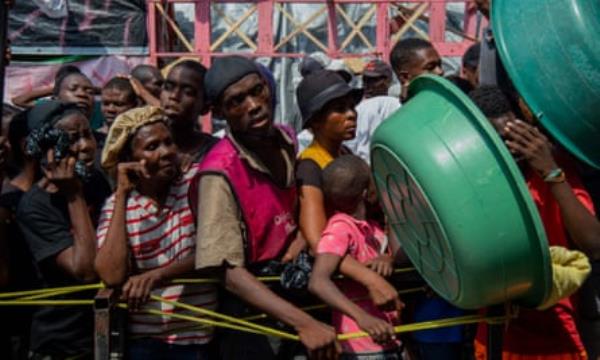 Haitians wait in a queue for food 