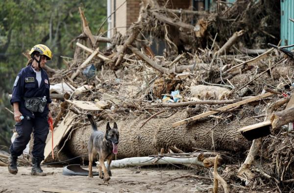 A member of the FEMA Urban Search and Rescue Task Force with a search canine inspecting a flood-damaged property in Asheville, North Carolina after Hurricane Helene