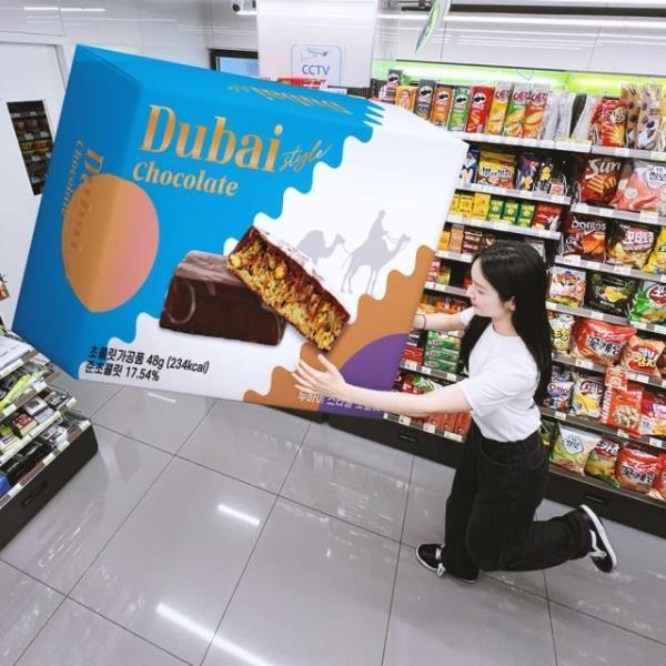 A　CU　employee　showcases　a　large　model　box　of　Dubai-style　chocolate,　which　launched　on　July　6.　The　initial　stock　of　200,000　units　sold　out　on　the　same　day　(Courtesy　of　CU)