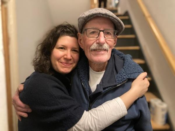 Sharone hugging her father in the landing of a building